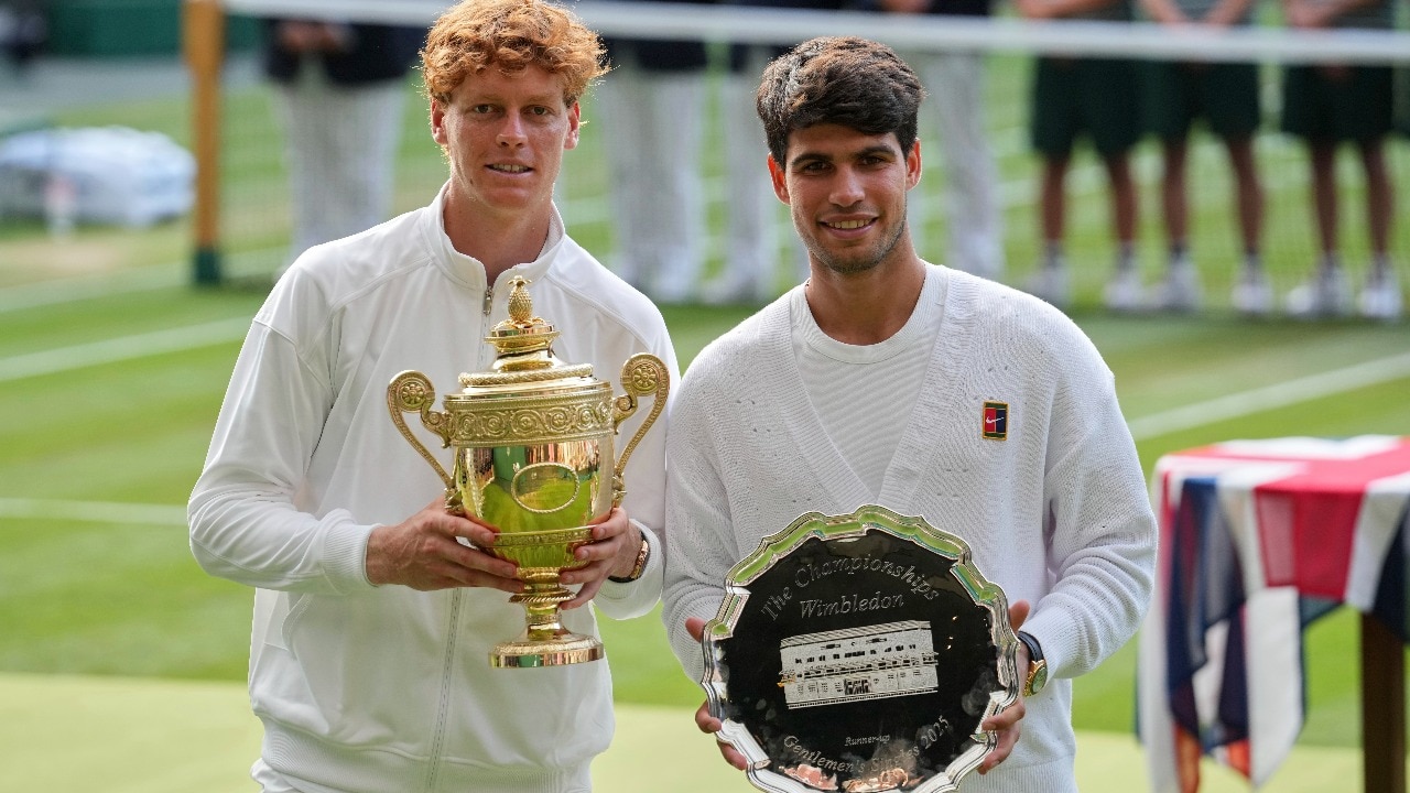 Italy's Jannik Sinner, left, celebrates with the trophy after beating Carlos Alcaraz of Spain, right, to win the men's singles final at the Wimbledon Tennis Championships in London, Sunday, July 13, 2025. (AP Photo/Kin Cheung)